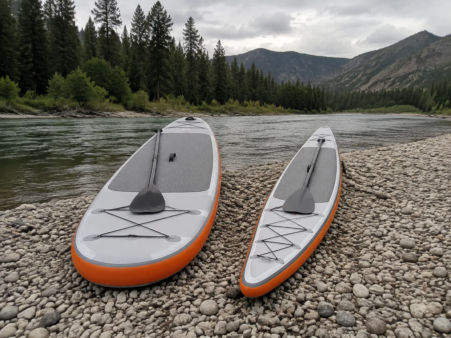 Two paddle board shapes beside a mountain river